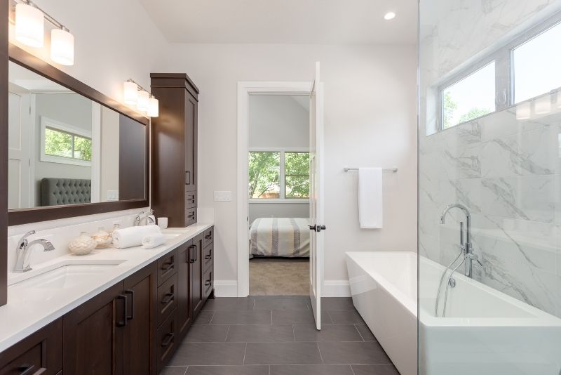 warm tiled bathroom with large mirror that has lights on top