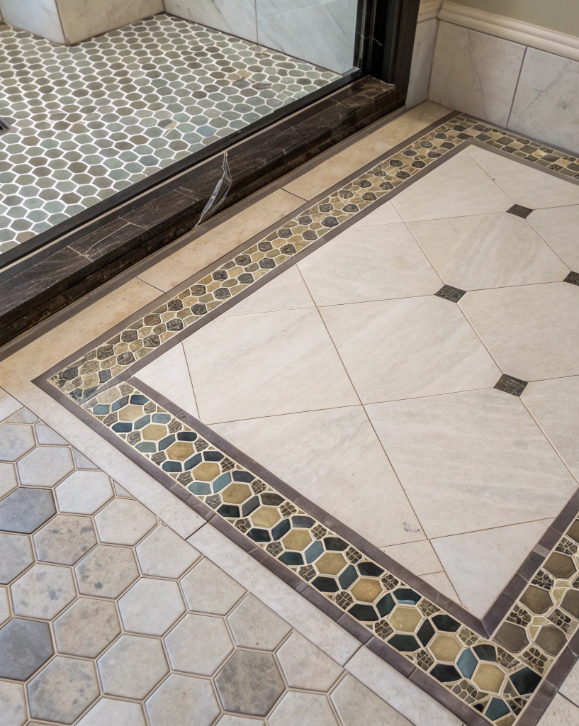 Bathroom floor detail showing a decorative mosaic tile border pattern