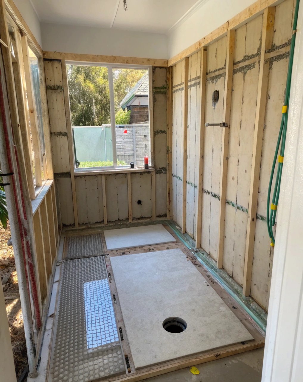 Bare shower recess mid-renovation showing exposed wall framing